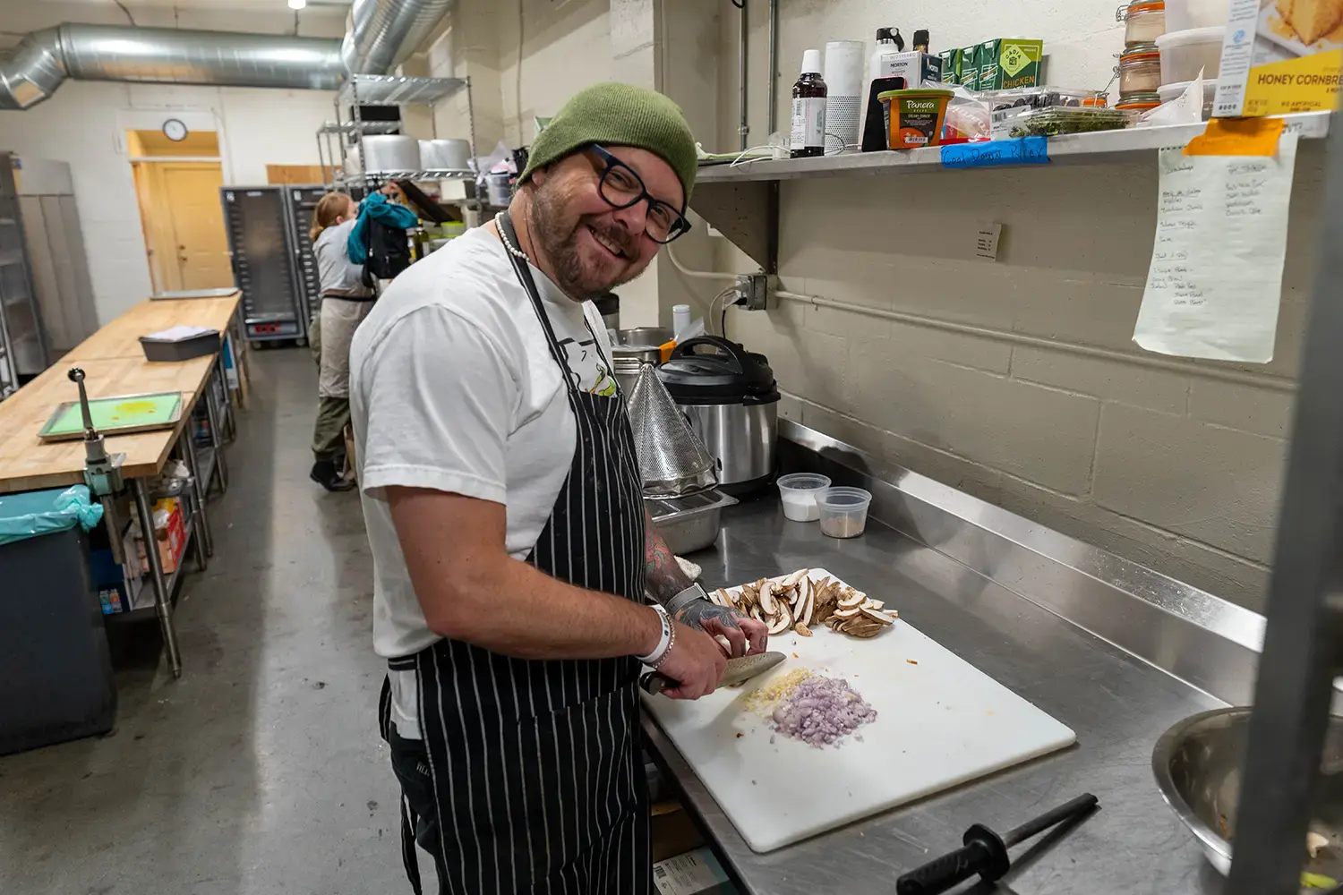 An image of a chef chopping mushrooms at a side workstation